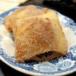 A plate of finished sopapillas rolled in cinnamon sugar.