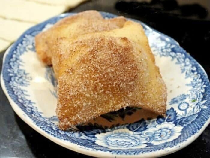 A plate of finished sopapillas rolled in cinnamon sugar.