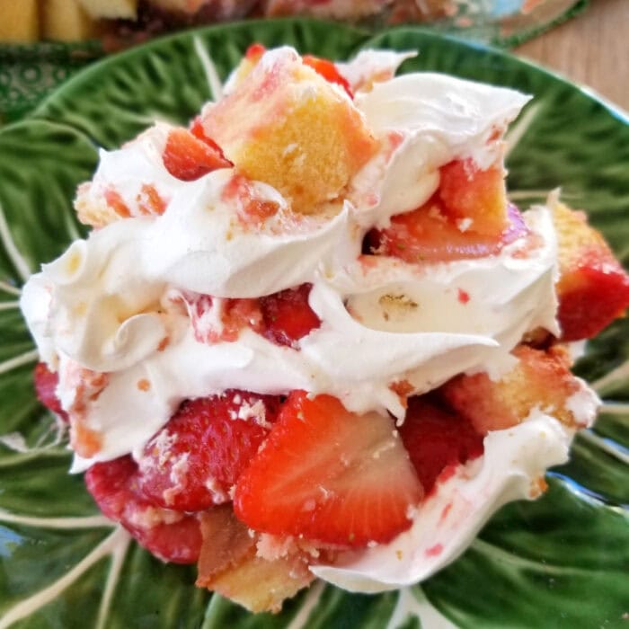 An easy layered dessert with strawberries, cool whip, and cake shown on a green plate.
