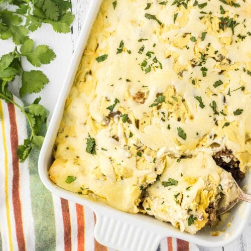 Overhead view of green chile enchiladas in a casserole dish.