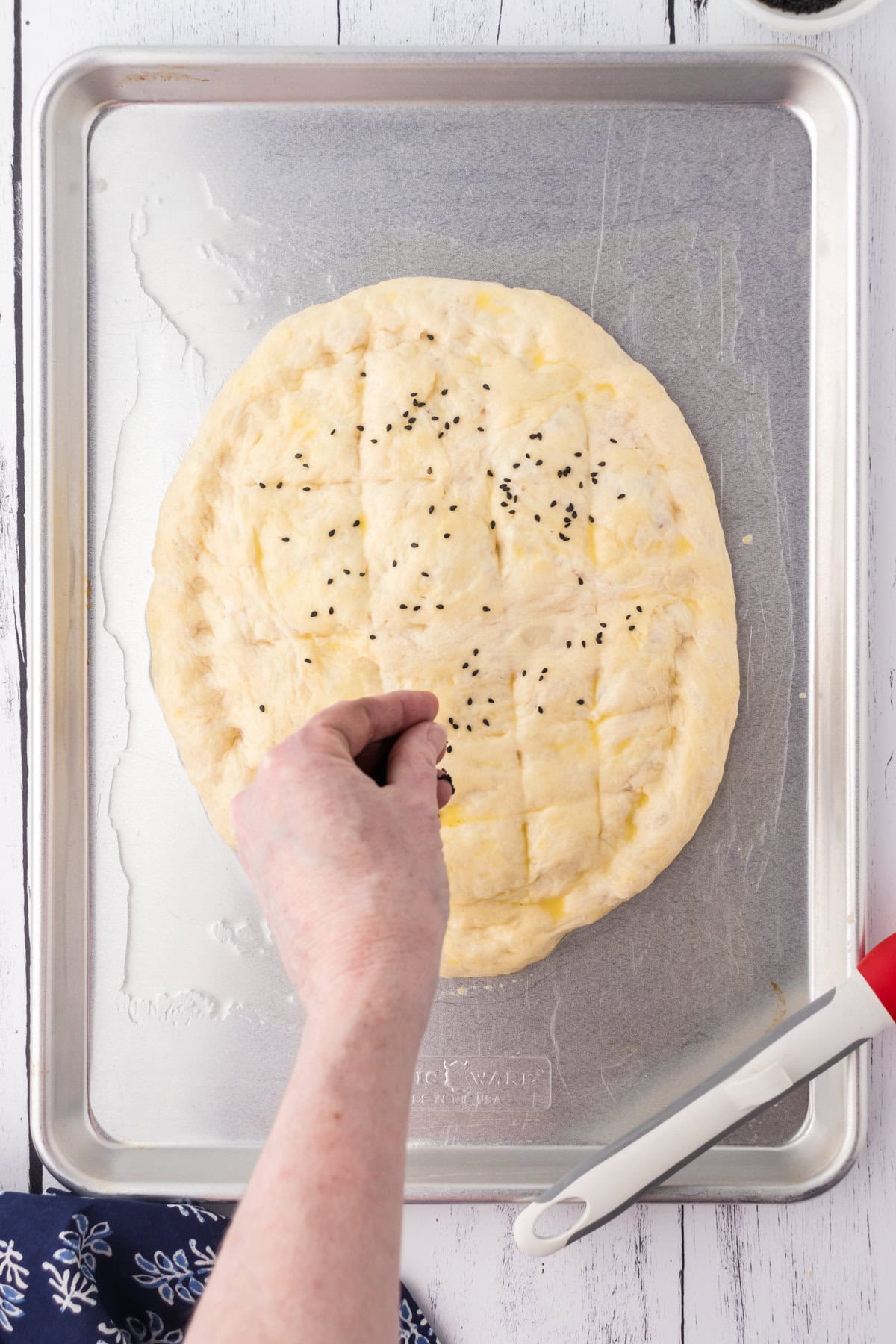 Black sesame seeds being added to the top of the dough.