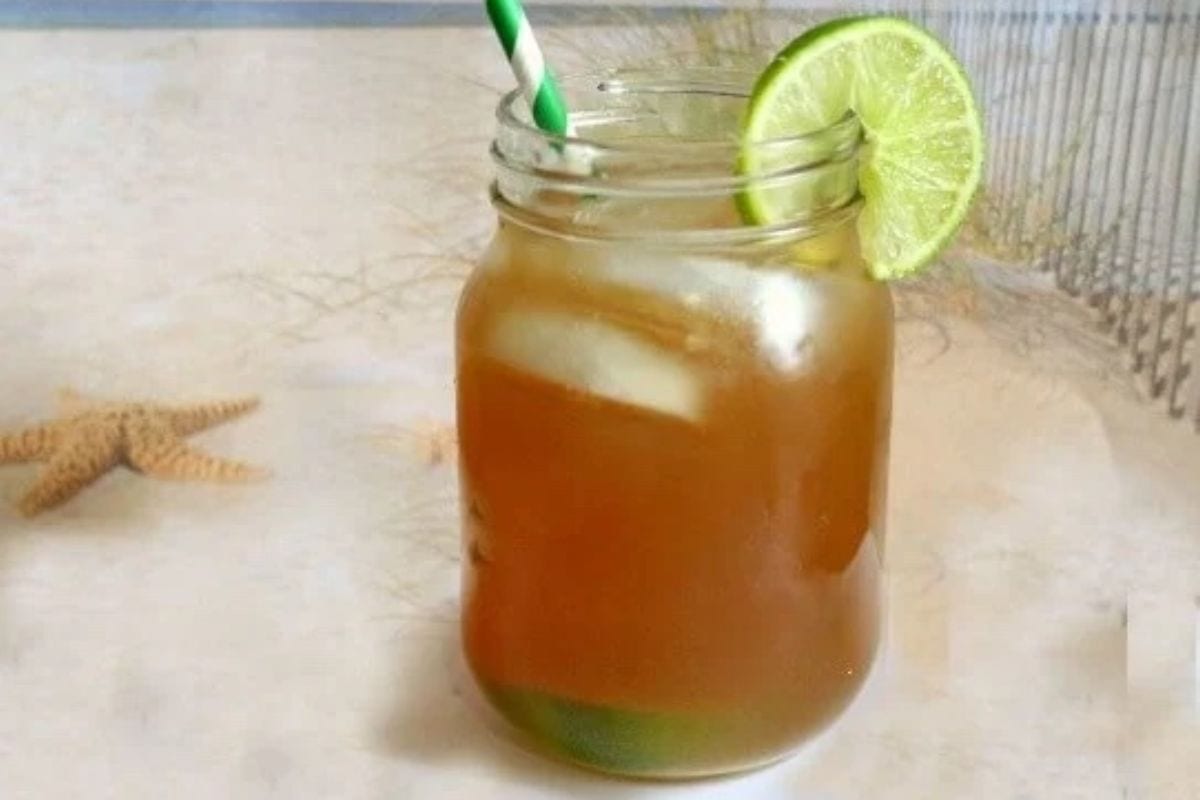 A glass of Long Island Iced Tea on a beach.