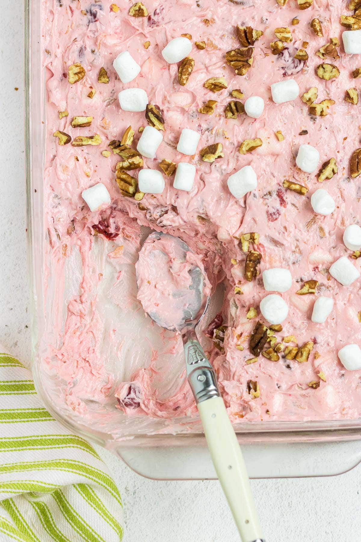 Overhead view of fluffy, pink junkyard salad with a serving removed.