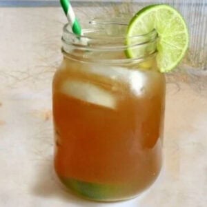 A closeup of a glass of Long Island Iced Tea on a beach.
