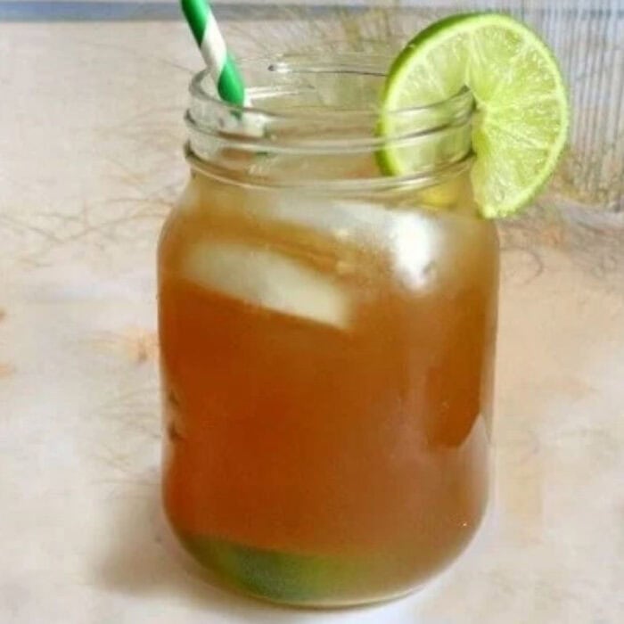 A closeup of a glass of Long Island Iced Tea on a beach.