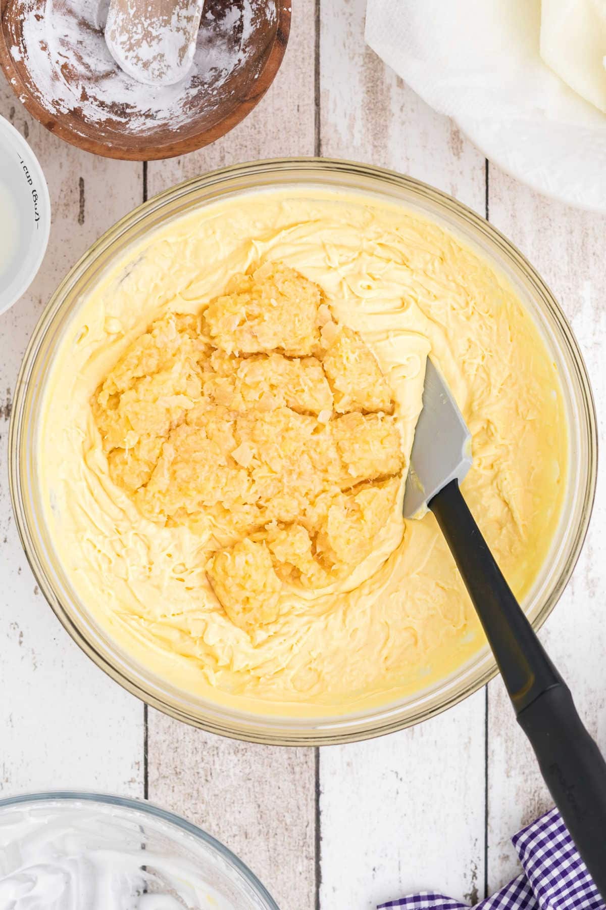 Pineapple being folded into pudding mixture.