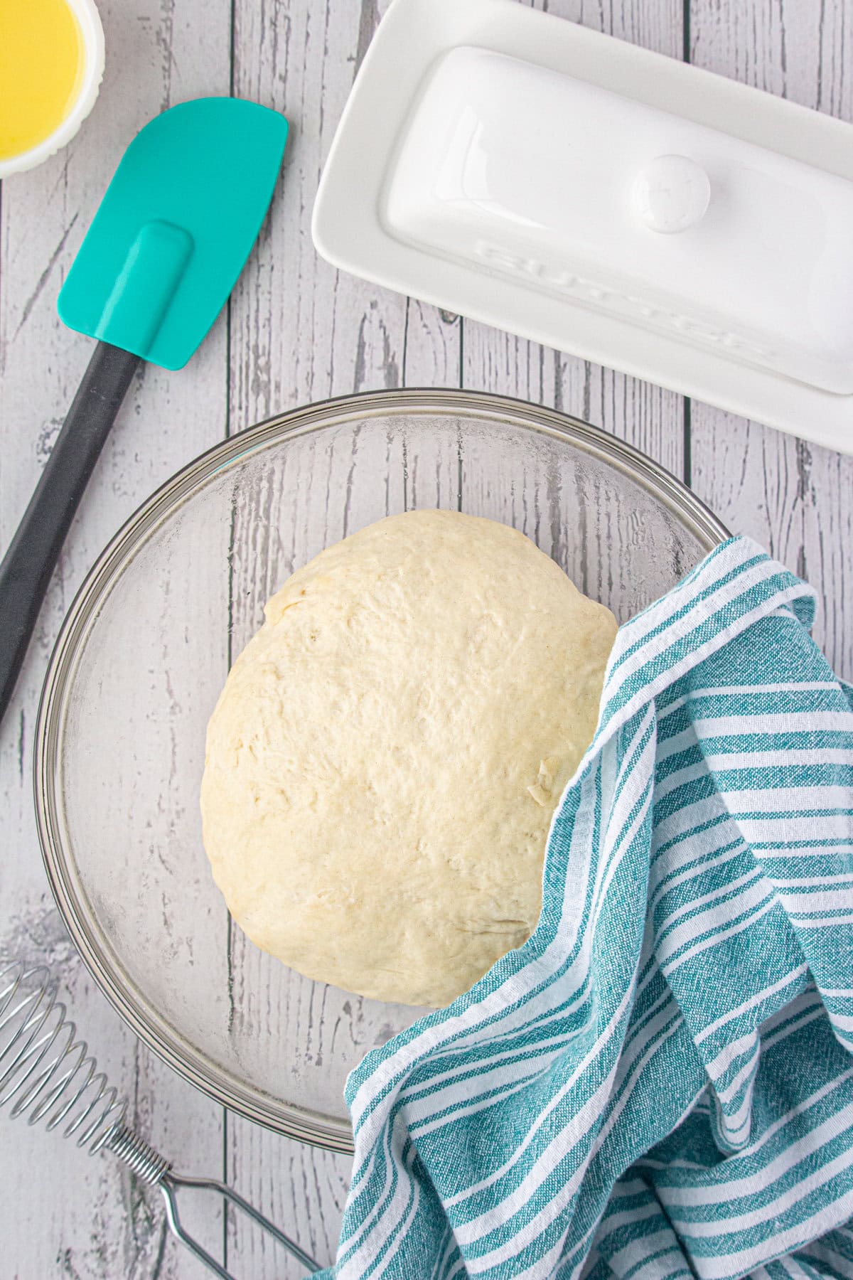 The ball of dough rising in a glass bowl.