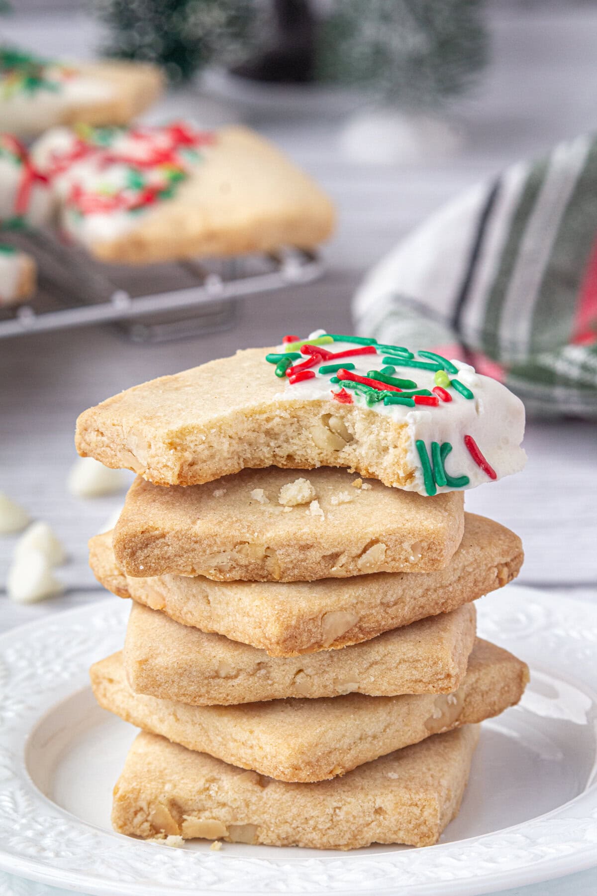 Sprinkled Christmas Hawaiian shortbread cookies stacked on each other on a plate.