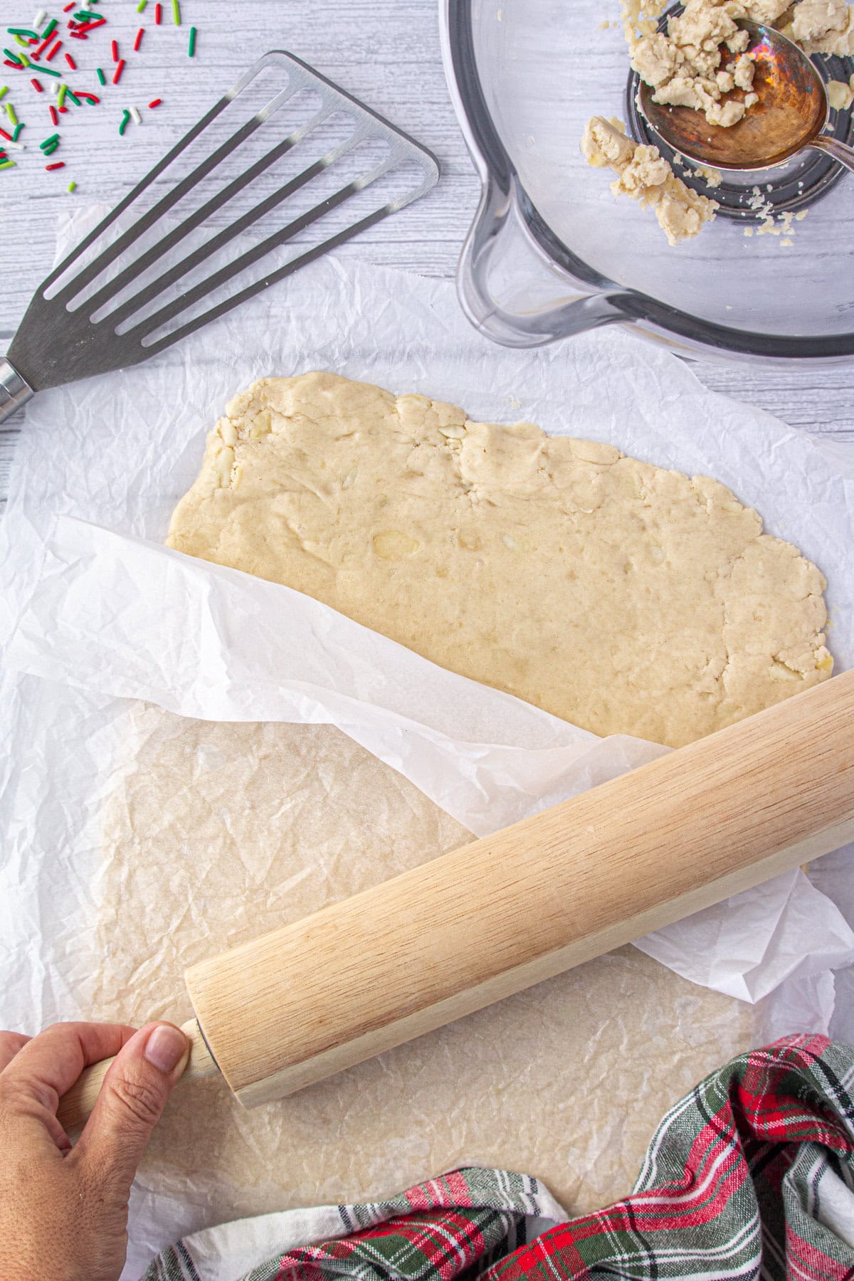 Rolling out the shortbread dough between parchment papers sheets.