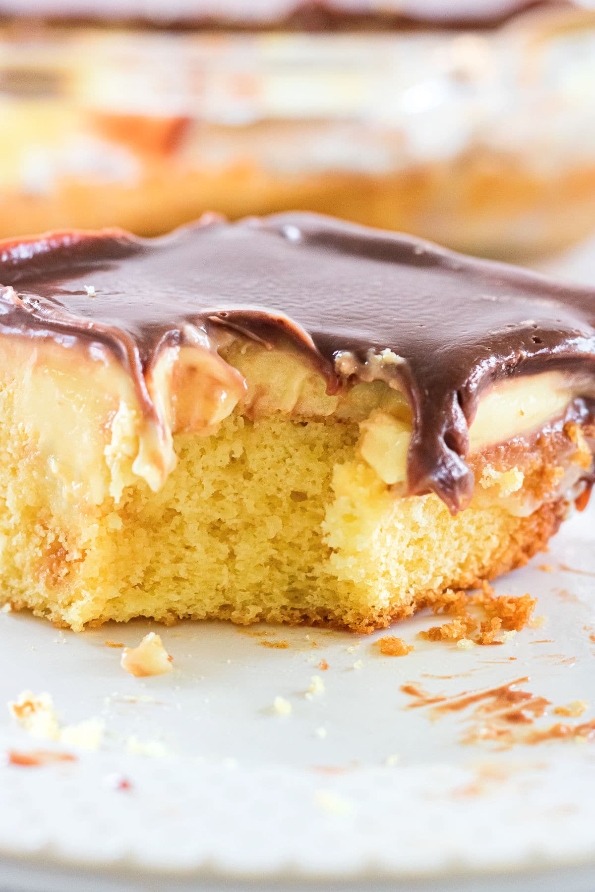 Cake with bite taken out of it showing the layers of cake, pudding, and chocolate ganache glaze.