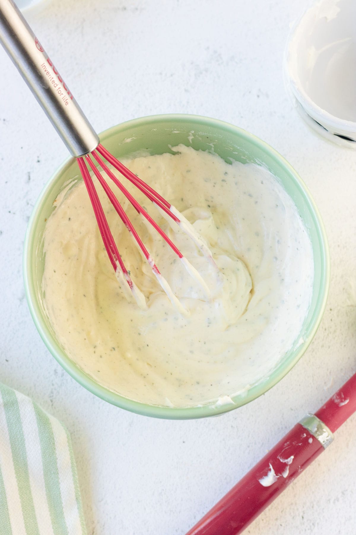 A whisk in a bowl of finished dressing for this salad.