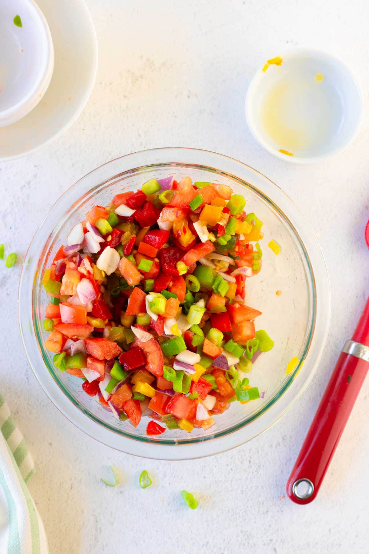 Vegetables, including tomatoes, peppers, and onions, chopped up in a bowl.