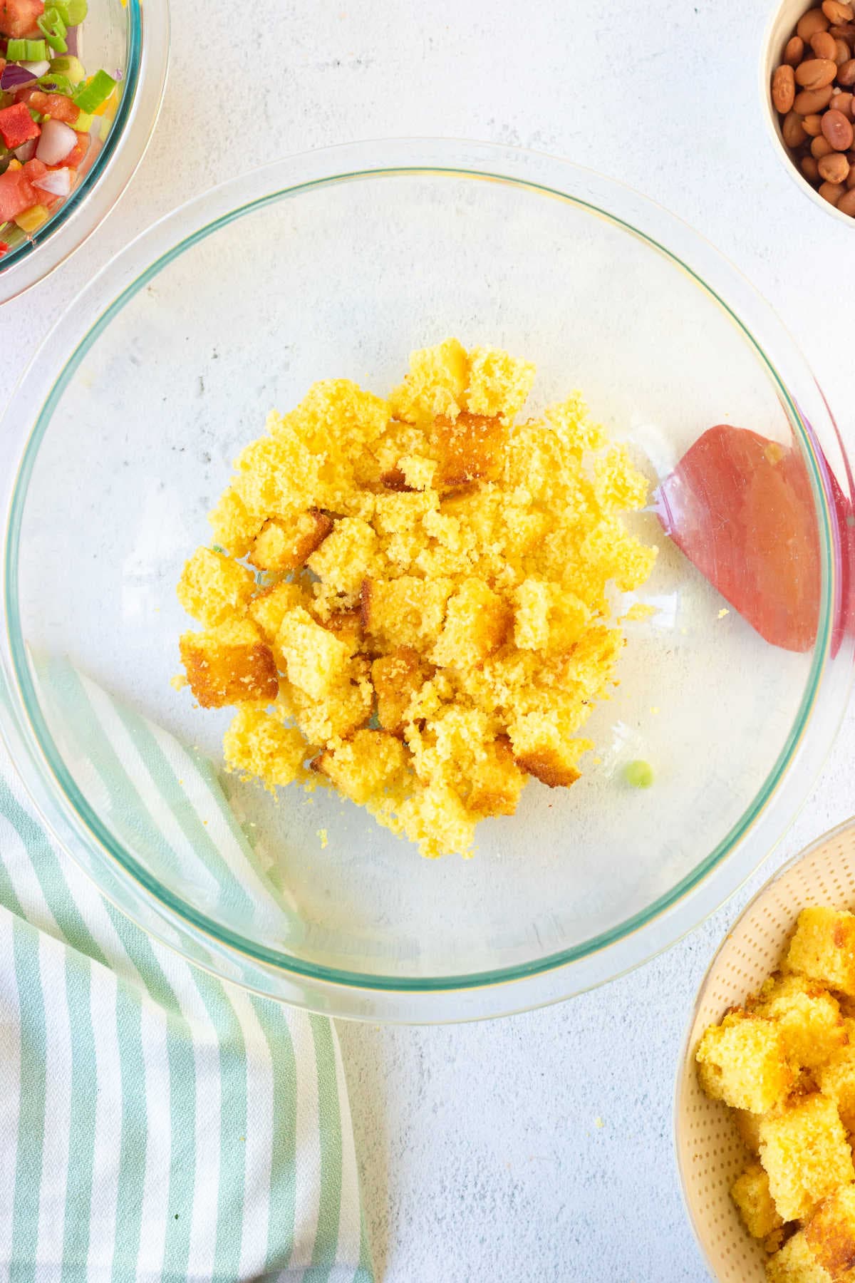 Cornbread being cubed and added to a serving bowl.