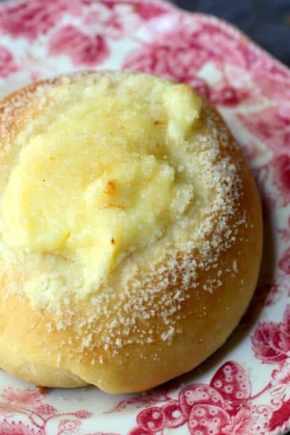 Closeup of a cream cheese kolache on a red transferware plate.