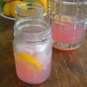 A glass of lavender lemonade cocktail on a table.