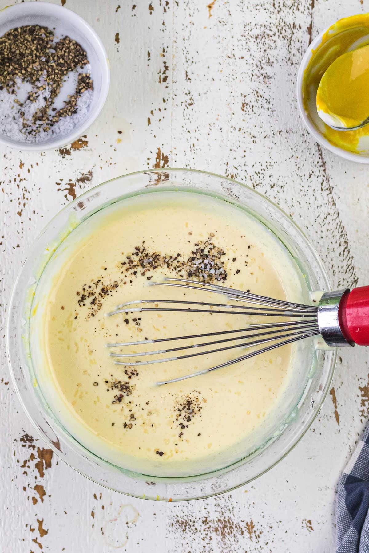 The ingredients for the dressing in a glass bowl being whisked smooth.