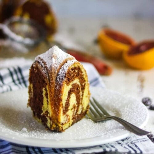 A slice of marble pound cake on a plate with a fork.
