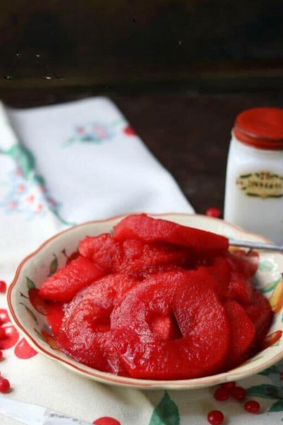 Bowl of bright red cinnamon apple rings on a table.