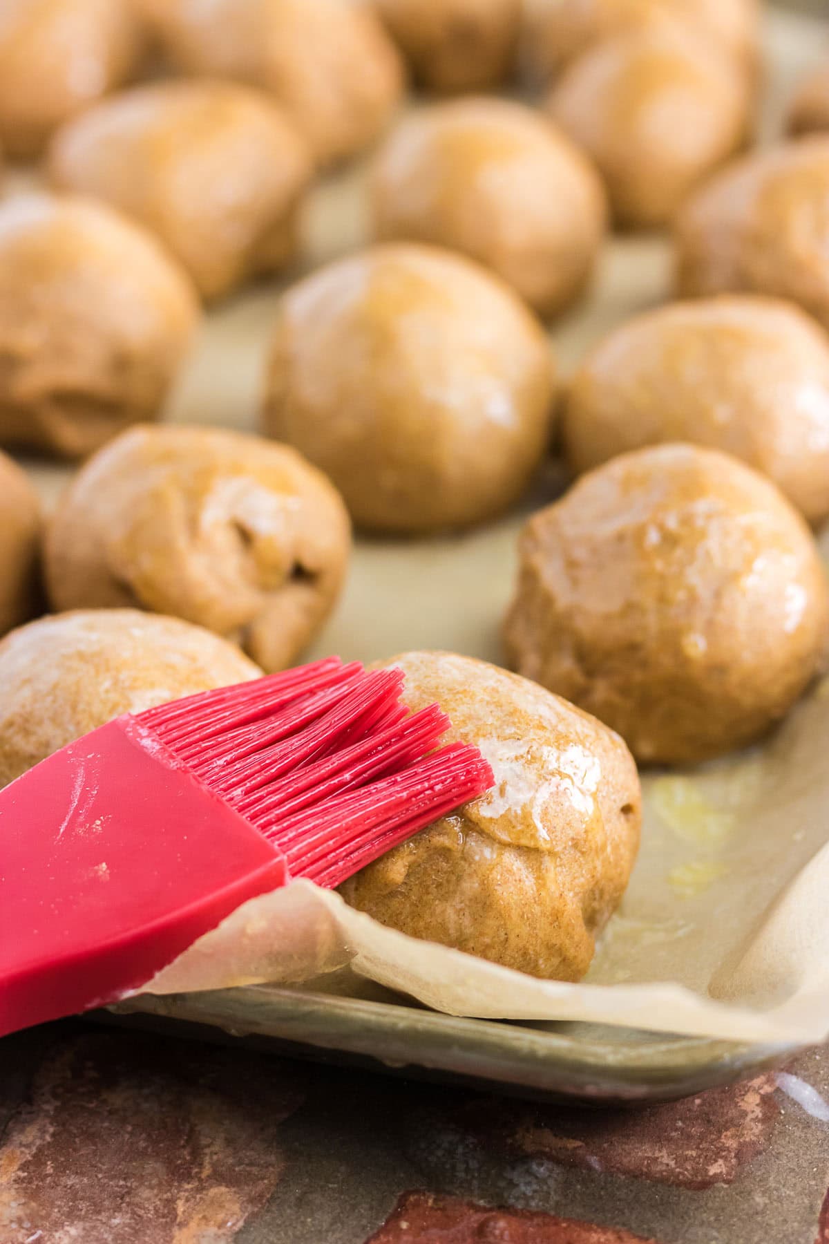 Dough has been formed into rolls and is being brushed with melted butter.
