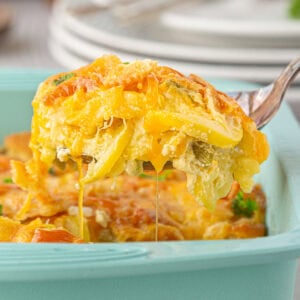 Closeup of a serving of cheesy Southern squash casserole being lifted from the dish.