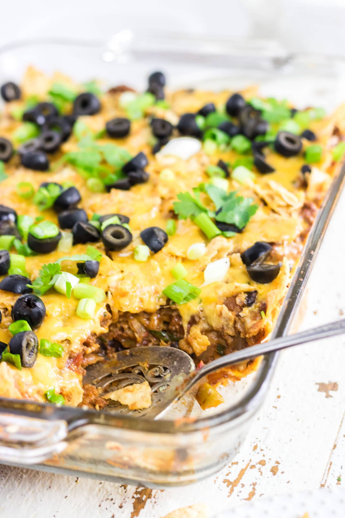 A close-up view of the beef nacho casserole with a serving spoon.