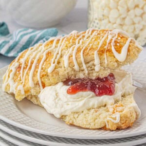 An apricot white chocolate scone split in half and filled with devonshire cream and strawberry jam.