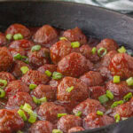 Cranberry meatballs in an iron skillet.