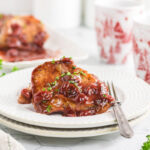 pork chops with a cherry sauce on a white plate.