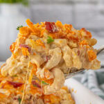 A serving of bacon pimento mac and cheese being lifted from the dish.