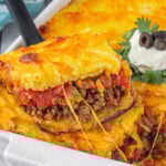 A serving of tamale pie being lifted from the casserole dish.