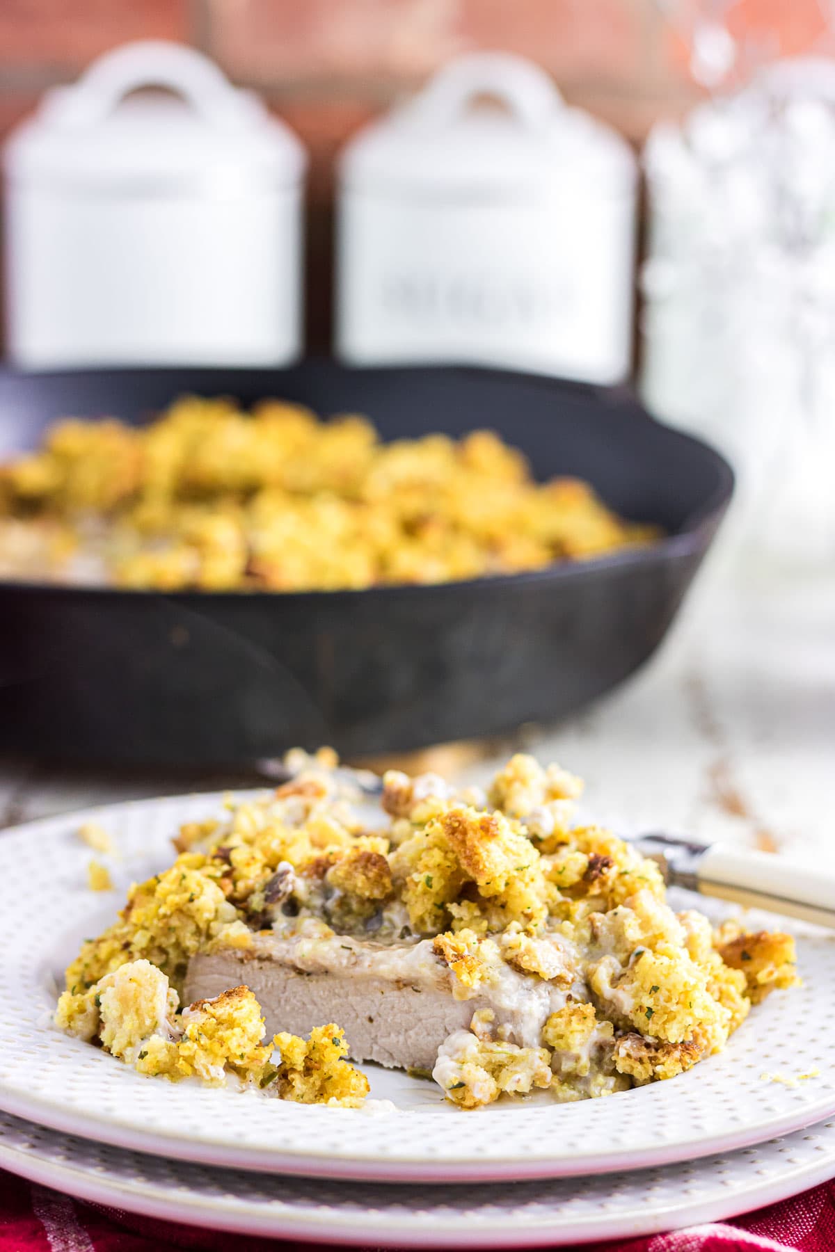 An up-close view of a sliced pork chop topped with gravy and cornbread stuffing.