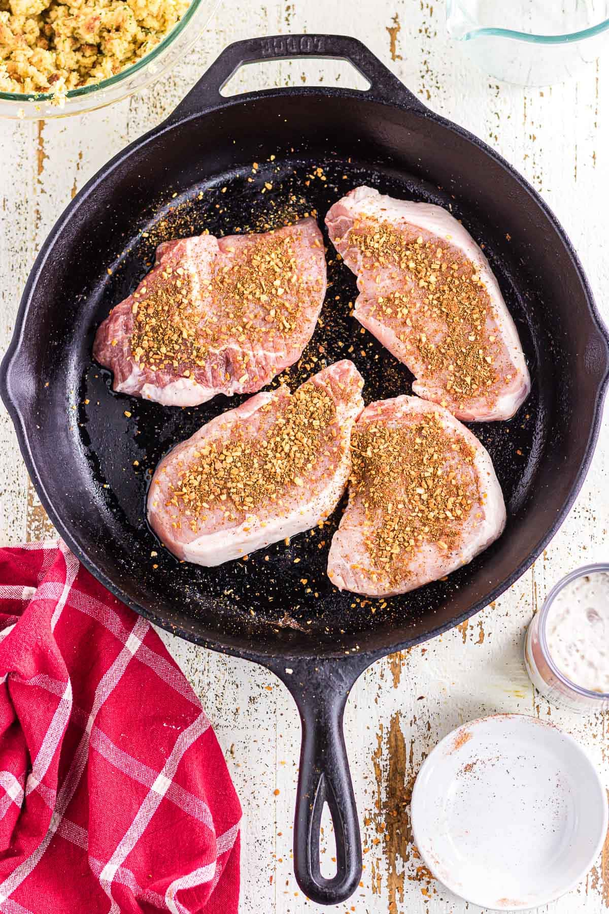 The seasoned pork chops in a greased slkillet.
