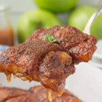 Apple dumplings being lifted from a baking dish.