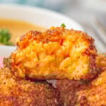 Closeup of pimento cheese balls cut in half to show the gooey cheese insides.