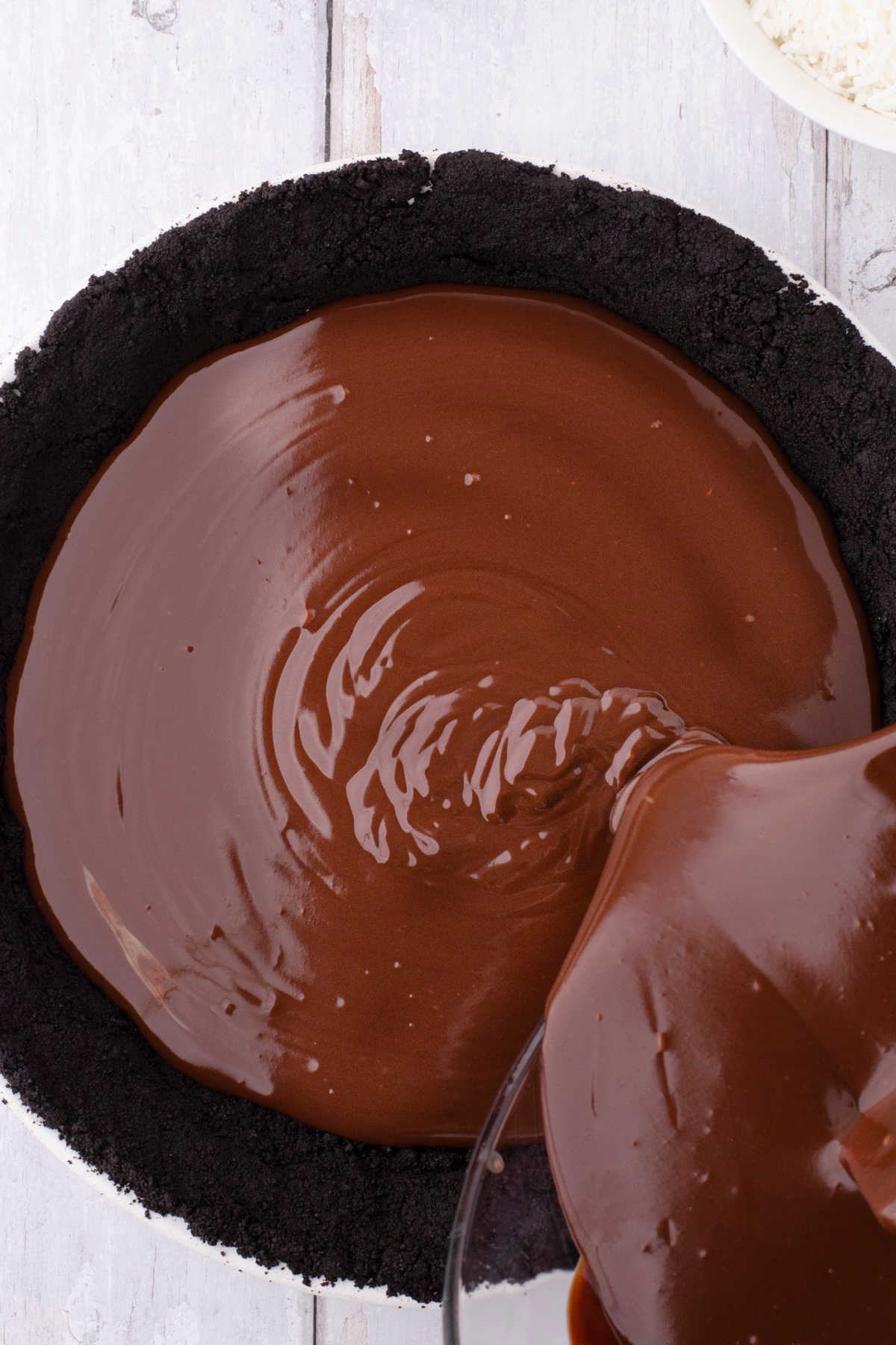 The chocolate mixture being poured into a chocolate crumb crust.