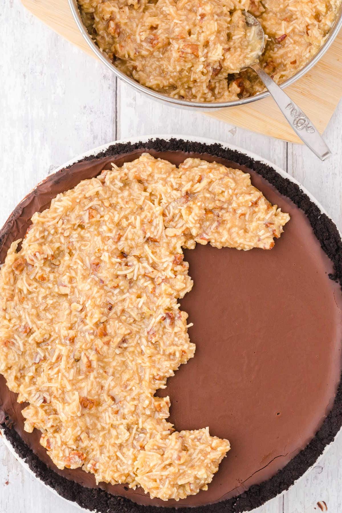 The coconut mixture being spooned on the top of the chocolate layer.