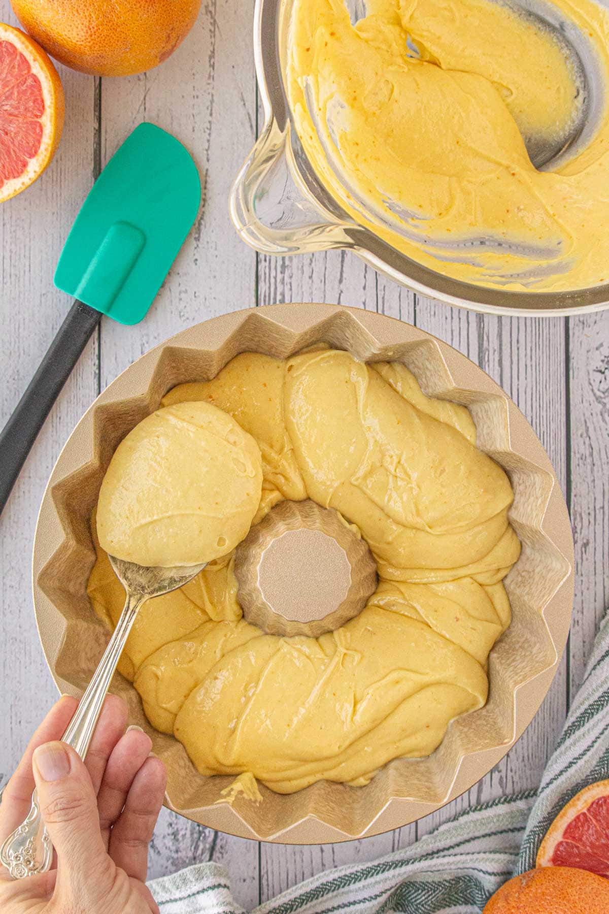 Cake batter being spooned into a bundt pan.