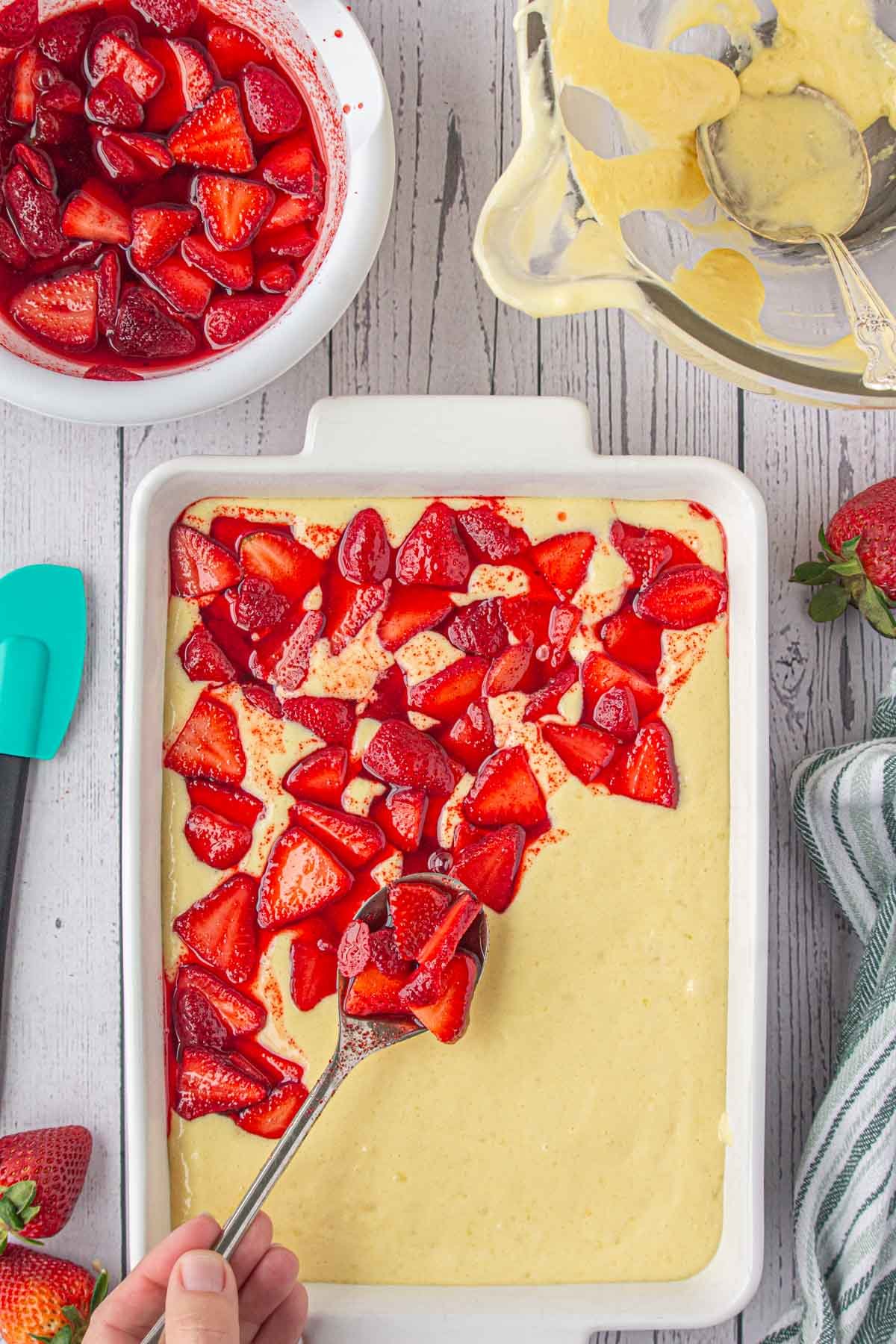 Strawberries being smoothed over cake batter.
