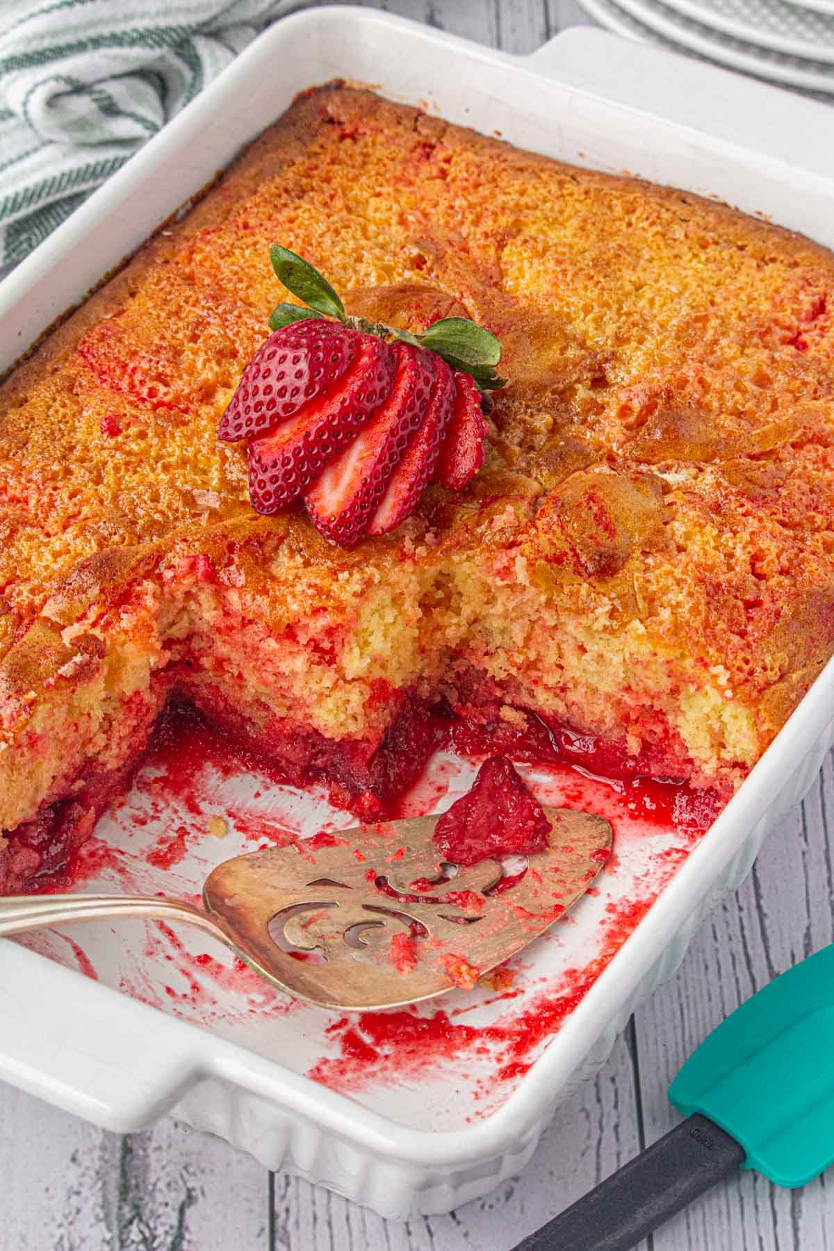 Strawberry shortcut cake in pan with servings removed to show the bottom layer.