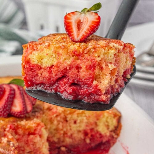 A square of strawberry shortcut cake being served from a spatula.