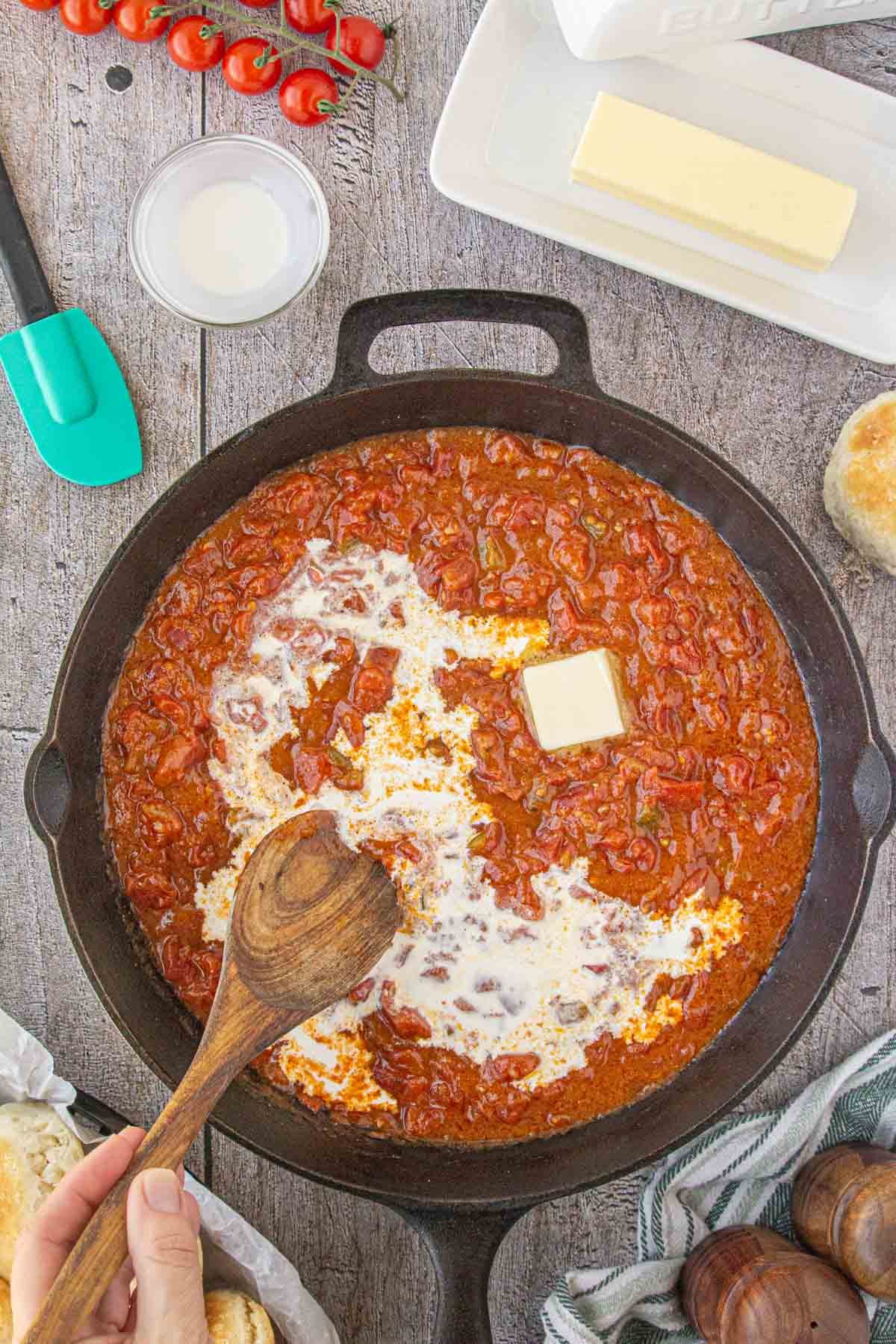 Cream and butter being added to tomato gravy.