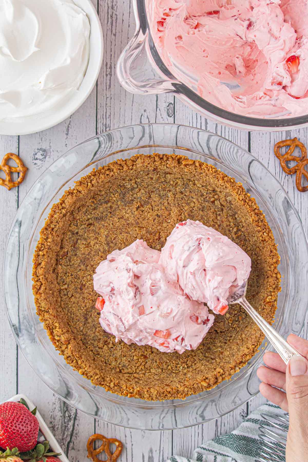 The strawberry mixture being spooned into the pie crust.