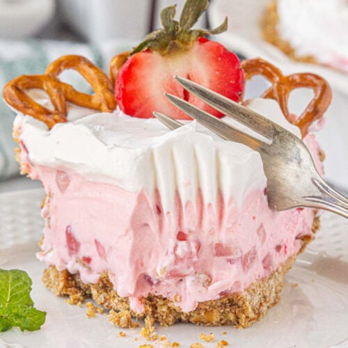 A slice of strawberry icebox pie being cut with a fork.