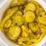 Overhead closeup of pickles in a white bowl.