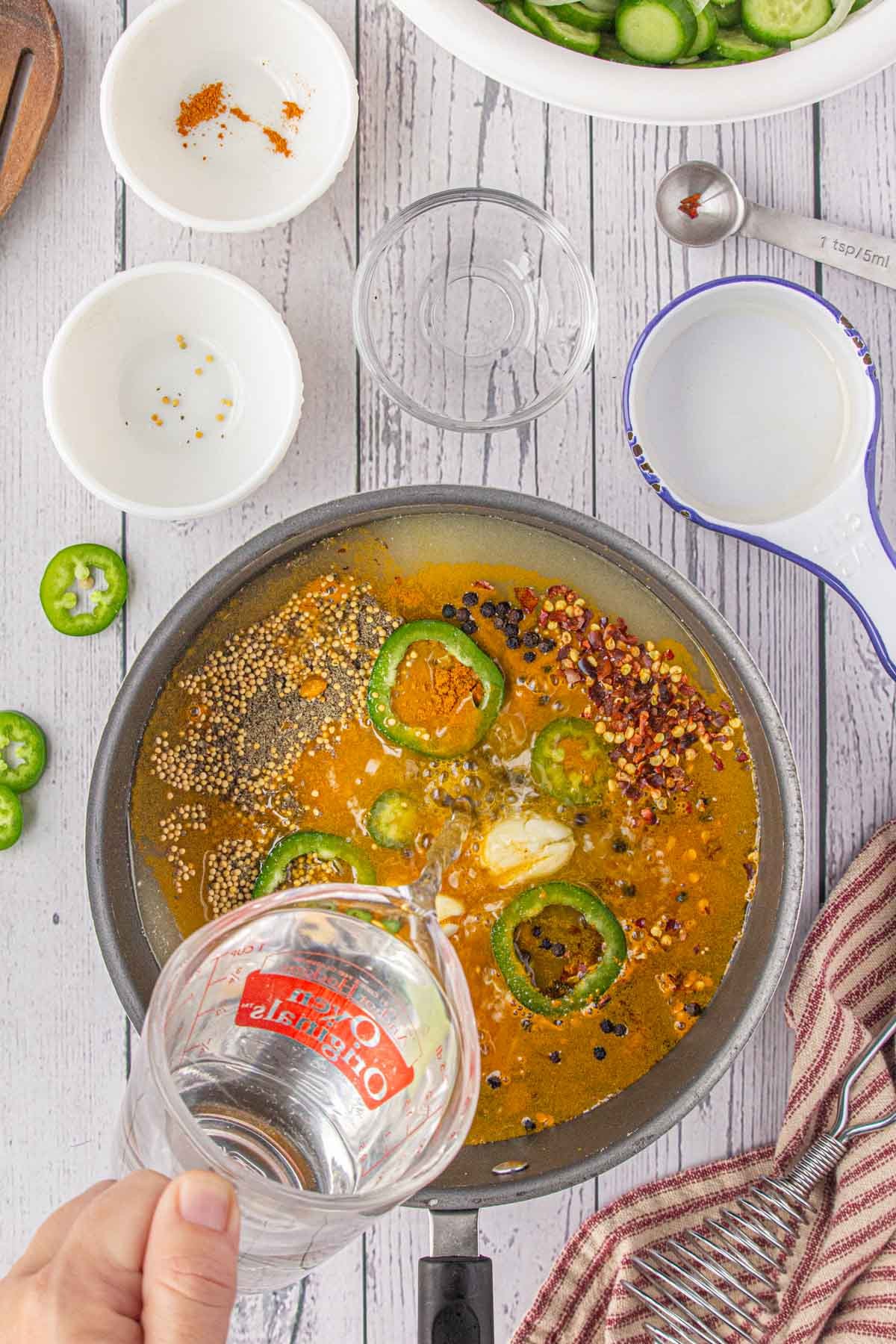 Vinegar being poured into the bowl of spices.