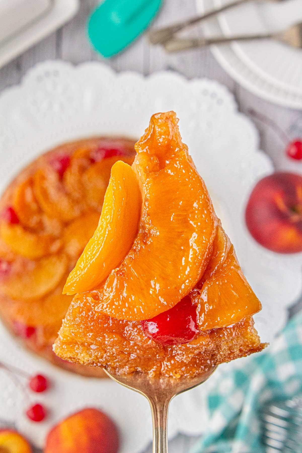 Homemade peach upside-down cake being served from a white cake plate.