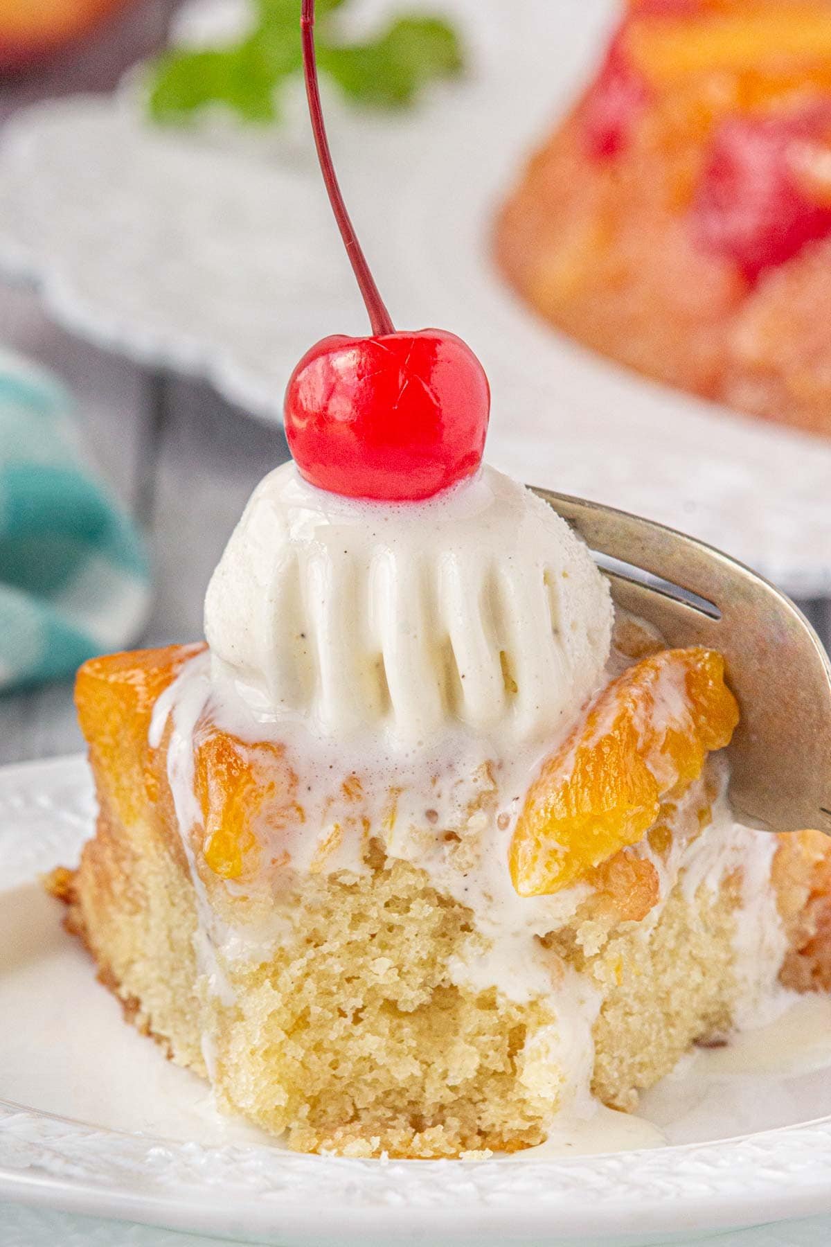 A square of peach upside down cake with ice cream on top.
