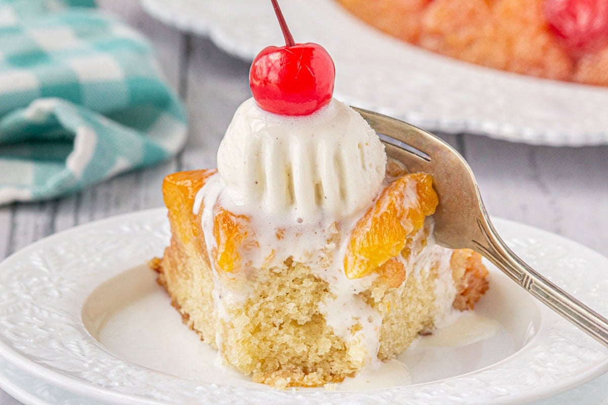A square of peach upside-down cake with ice cream on top.