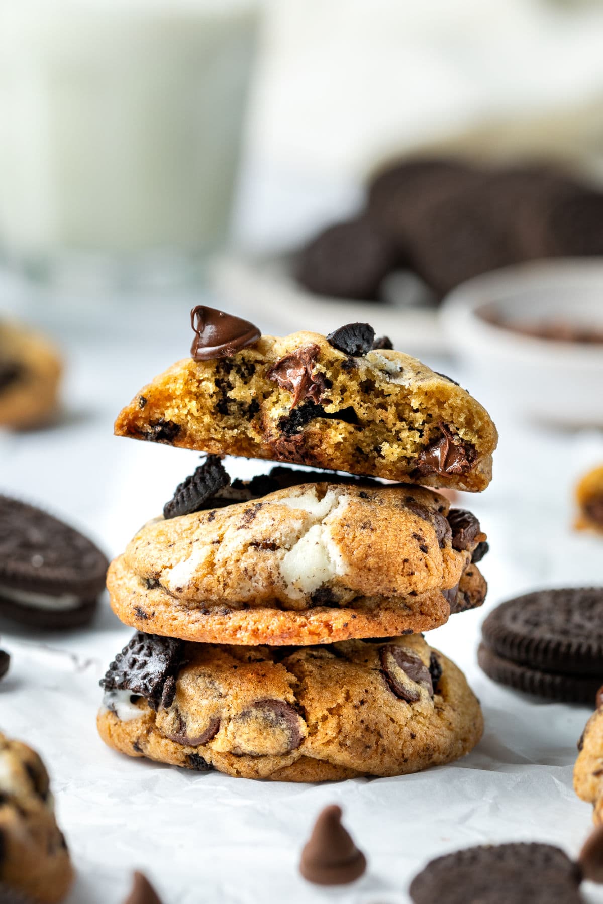 A stack of gooey Oreo and chocolate chip cookies ready to be eaten with a cold glass of milk.