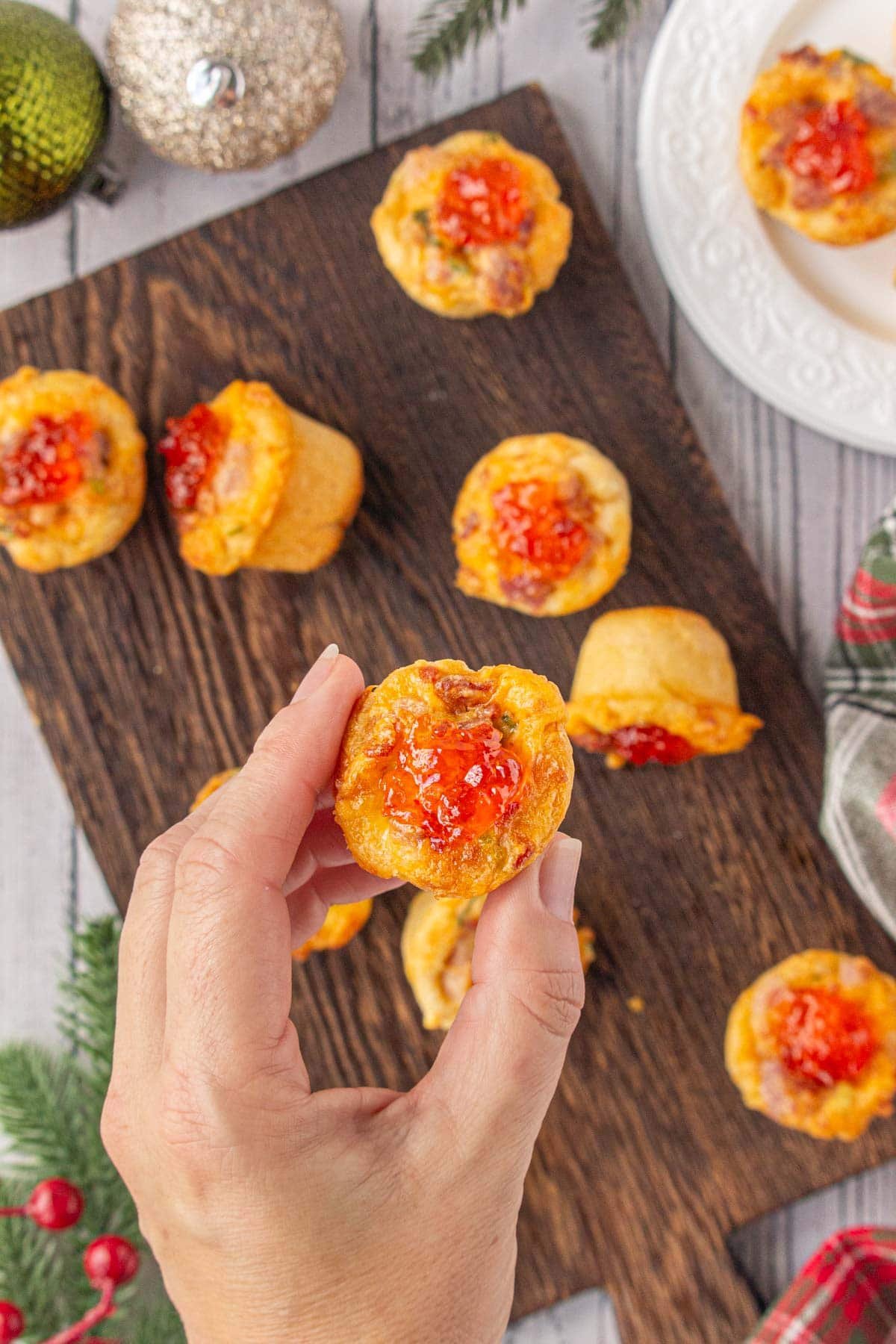 Closeup of a cheddar ham cup appetizer in someone's hand.